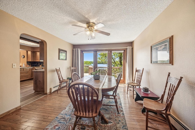 12975 185th St, Cold Spring, MN 56320 - dining space featuring a baseboard heating unit, wood-type flooring, ceiling fan, a textured wall, and a textured ceiling