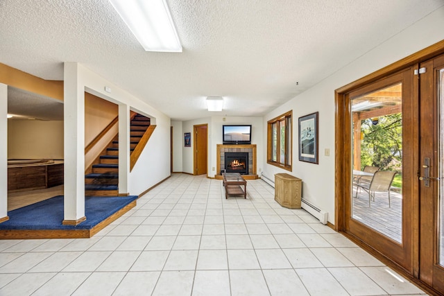 12975 185th St, Cold Spring, MN 56320 - unfurnished living room with a textured ceiling, a tiled fireplace, stairs, a baseboard radiator, and baseboards