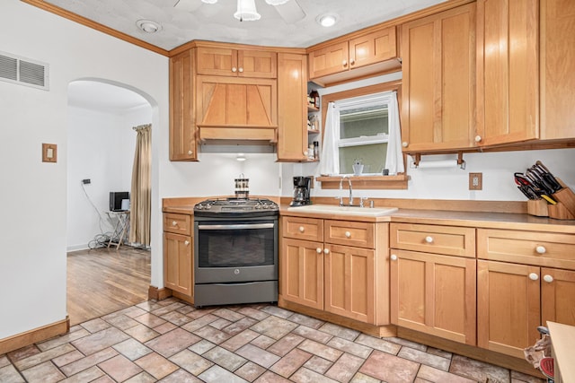 1344 Schletti St, Saint Paul, MN 55117 - kitchen with stainless steel range with gas cooktop, custom exhaust hood, a sink, arched walkways, and light countertops