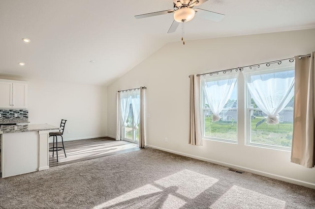 39685 Fallbrook Ave, North Branch, MN 55056 - unfurnished living room with plenty of natural light, vaulted ceiling, baseboards, light colored carpet, and a ceiling fan