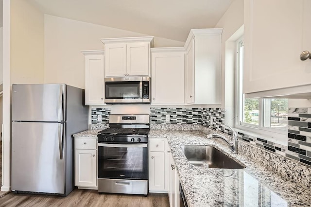 39685 Fallbrook Ave, North Branch, MN 55056 - kitchen featuring appliances with stainless steel finishes, a sink, lofted ceiling, white cabinetry, and decorative backsplash