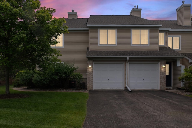 2225 Ranchview Ln N Unit 1, Plymouth, MN 55447 - view of front of house featuring an attached garage, asphalt driveway, a front lawn, a chimney, and brick siding