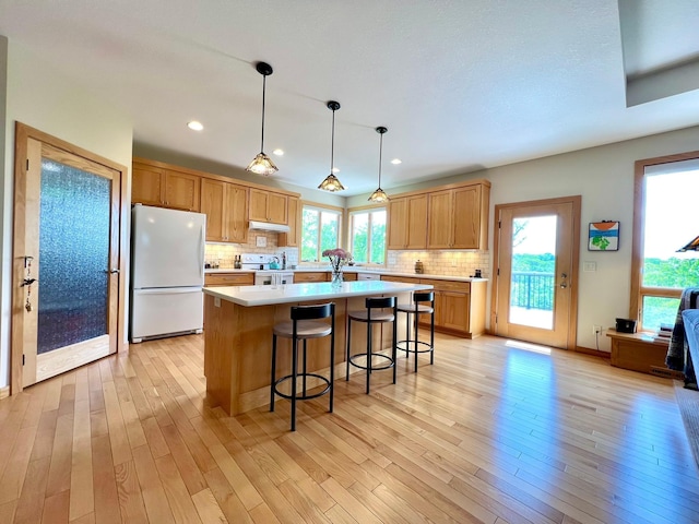 2774 Pine Ridge Blvd, Red Wing, MN 55066 - kitchen featuring white appliances, a center island, light countertops, a breakfast bar area, and under cabinet range hood