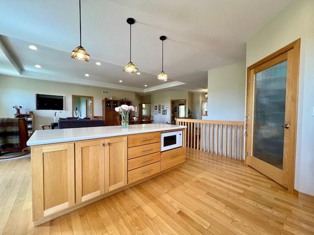 2774 Pine Ridge Blvd, Red Wing, MN 55066 - kitchen featuring white microwave, a raised ceiling, open floor plan, light wood-style flooring, and light brown cabinets