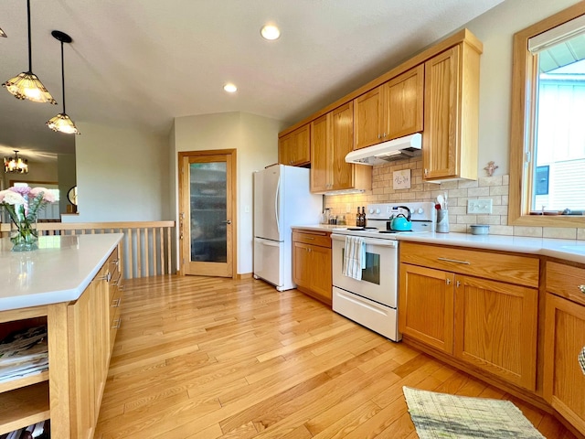 2774 Pine Ridge Blvd, Red Wing, MN 55066 - kitchen with white appliances, under cabinet range hood, light wood finished floors, light countertops, and backsplash