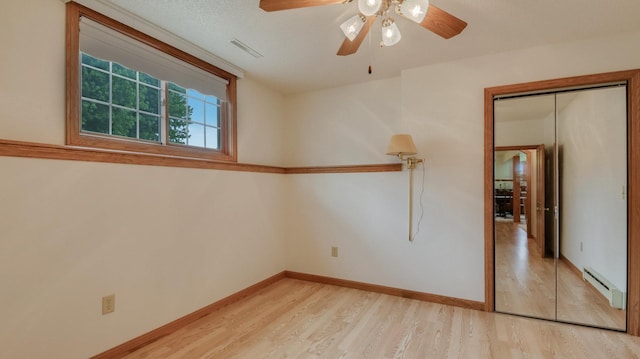 9020 120th Ave, Tilden Twp, WI 54724 - unfurnished room featuring a baseboard radiator, light wood-style flooring, ceiling fan, and baseboards