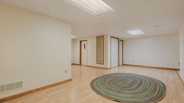 9020 120th Ave, Tilden Twp, WI 54724 - unfurnished room with built in shelves, baseboards, light wood-style floors, and a drop ceiling