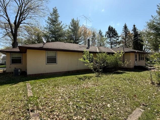 510 2nd Ave NW, Milaca, MN 56353 - view of property exterior featuring a lawn, central air condition unit, and stucco siding