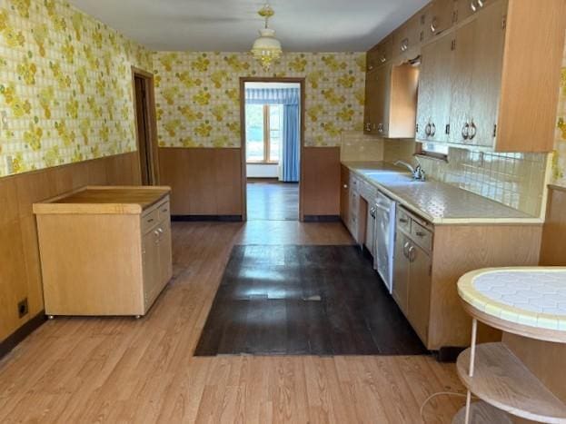 510 2nd Ave NW, Milaca, MN 56353 - kitchen featuring wallpapered walls, wainscoting, light countertops, light wood-style floors, and a sink
