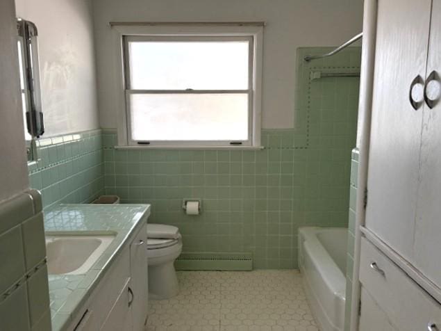 510 2nd Ave NW, Milaca, MN 56353 - bathroom featuring a baseboard heating unit, tile walls, vanity, tile patterned floors, and toilet