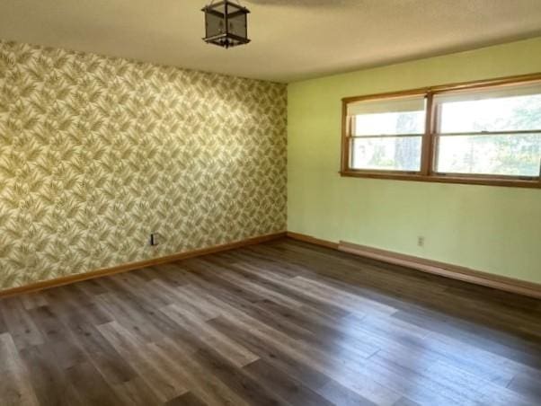 510 2nd Ave NW, Milaca, MN 56353 - unfurnished room featuring baseboards, wallpapered walls, and wood finished floors