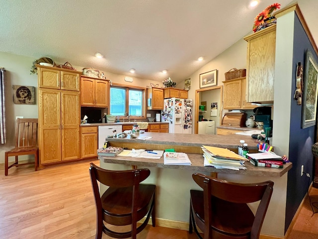 964 Aurora Cir, Red Wing, MN 55066 - kitchen with white appliances, washer and dryer, a peninsula, light wood-style flooring, and a kitchen bar