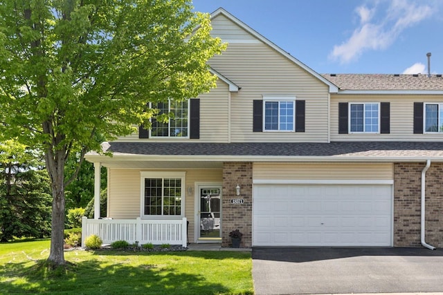 18571 98th Ave N, Maple Grove, MN 55311 - view of front facade featuring covered porch, driveway, brick siding, and a front yard