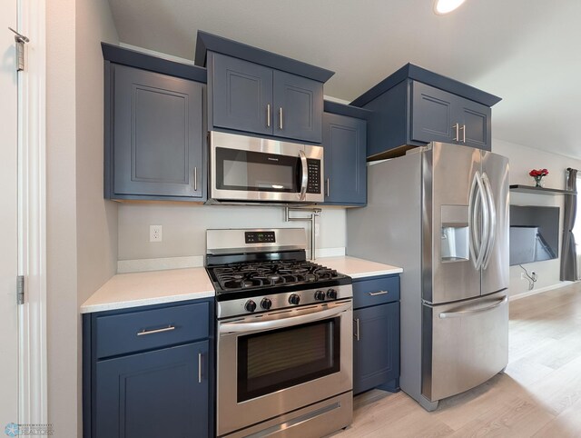 1506 67th Ave S, Fargo, ND 58104 - kitchen with stainless steel appliances, light wood-style flooring, light countertops, and blue cabinetry