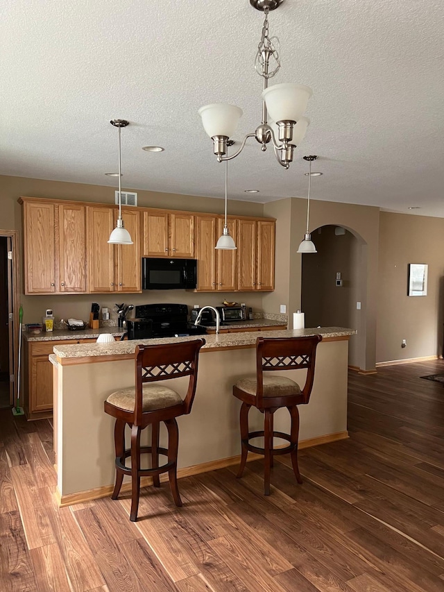 18147 73rd Pl N, Maple Grove, MN 55311 - kitchen featuring black appliances, arched walkways, wood finished floors, a textured ceiling, and pendant lighting