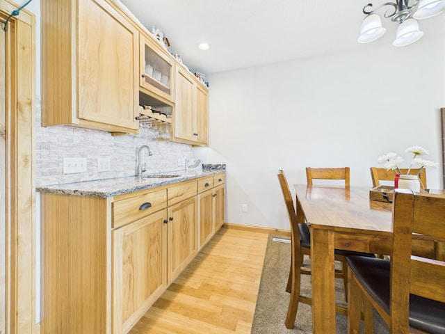 25797 Silver Beach Rd, Minnewaska Twp, MN 56334 - kitchen with light brown cabinetry, tasteful backsplash, light wood-type flooring, glass insert cabinets, and light stone counters
