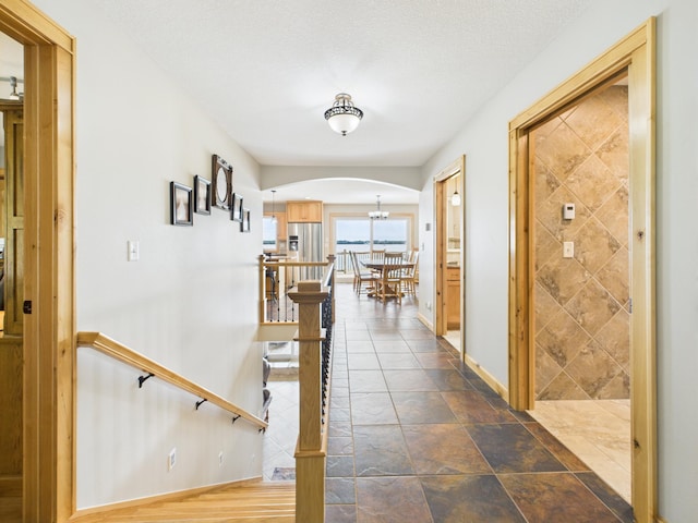 25797 Silver Beach Rd, Minnewaska Twp, MN 56334 - corridor with arched walkways, a chandelier, and dark stone finish floors