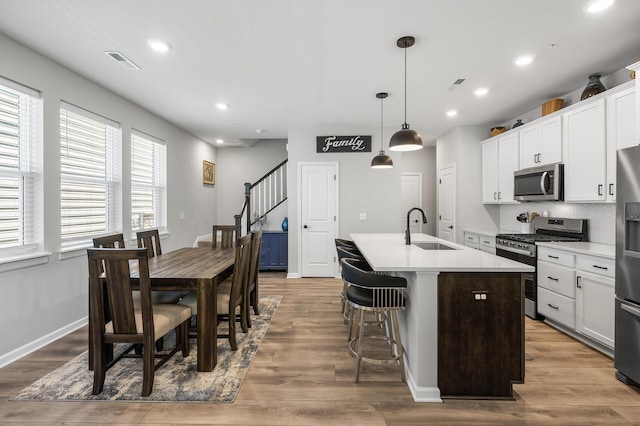 3011 Rum River Way, Anoka, MN 55303 - kitchen featuring appliances with stainless steel finishes, a sink, a center island with sink, light countertops, and white cabinetry