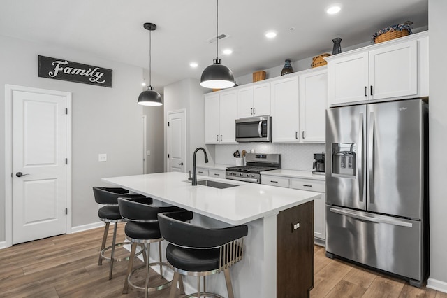 3011 Rum River Way, Anoka, MN 55303 - kitchen with appliances with stainless steel finishes, a kitchen island with sink, a sink, recessed lighting, and wood finished floors