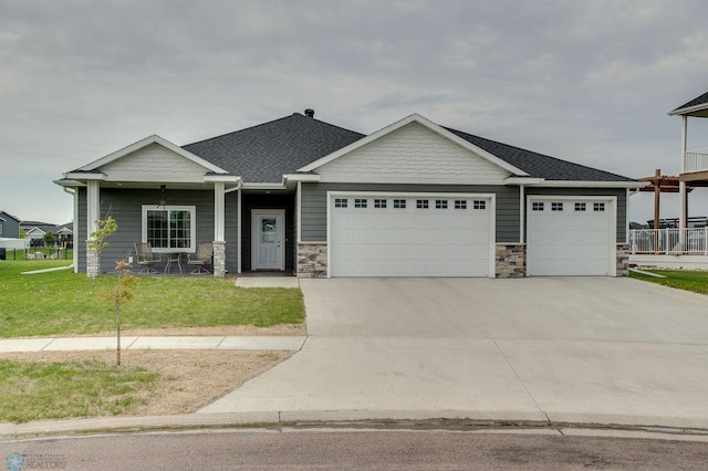 1908 65th Ave S, Fargo, ND 58104 - craftsman-style house with a garage, driveway, stone siding, a front lawn, and a shingled roof