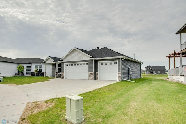1908 65th Ave S, Fargo, ND 58104 - view of front of house featuring an attached garage, a front lawn, stone siding, and driveway