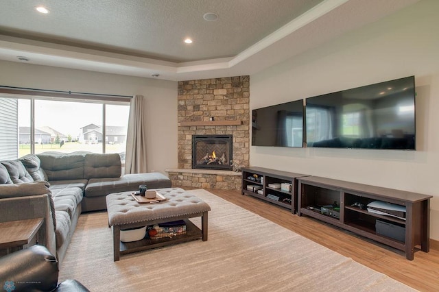 1908 65th Ave S, Fargo, ND 58104 - living room featuring wood finished floors, a raised ceiling, a stone fireplace, a textured ceiling, and recessed lighting