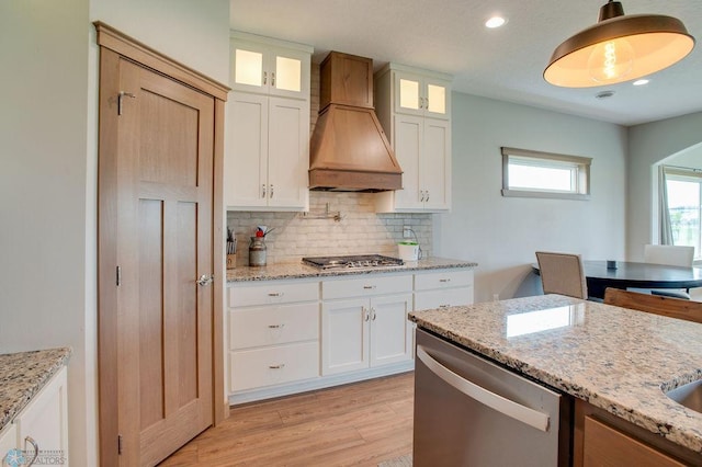 1908 65th Ave S, Fargo, ND 58104 - kitchen with appliances with stainless steel finishes, custom exhaust hood, decorative backsplash, light wood-style floors, and light stone counters
