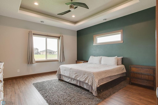 1908 65th Ave S, Fargo, ND 58104 - bedroom featuring a raised ceiling, wood finished floors, baseboards, multiple windows, and recessed lighting
