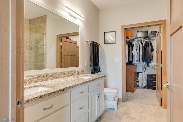 1908 65th Ave S, Fargo, ND 58104 - bathroom featuring double vanity, toilet, a spacious closet, and tiled shower