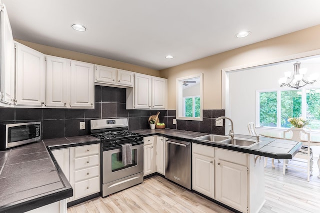 5725 Golden Valley Rd, Golden Valley, MN 55422 - kitchen featuring appliances with stainless steel finishes, a sink, dark countertops, a peninsula, and white cabinetry