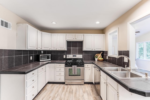 5725 Golden Valley Rd, Golden Valley, MN 55422 - kitchen with appliances with stainless steel finishes, a sink, white cabinets, light wood-type flooring, and recessed lighting
