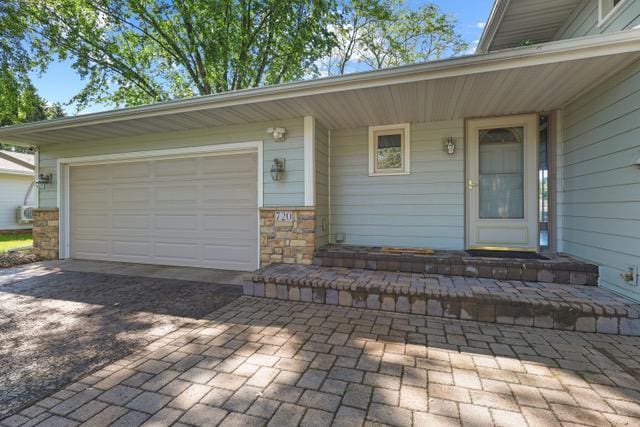 720 Tanglewood Dr, Shoreview, MN 55126 - view of exterior entry with driveway, a garage, and stone siding