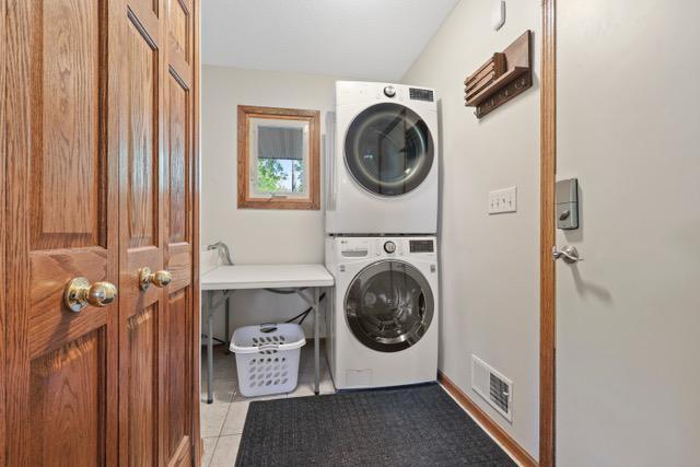 720 Tanglewood Dr, Shoreview, MN 55126 - laundry area with stacked washing machine and dryer and light tile patterned floors