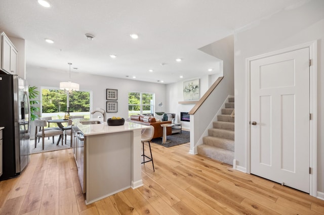 23221 Creekview Ct, Rogers, MN 55374 - kitchen featuring stainless steel refrigerator with ice dispenser, a sink, light countertops, light wood finished floors, and a kitchen breakfast bar