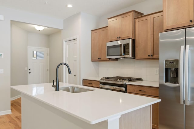 23221 Creekview Ct, Rogers, MN 55374 - kitchen with appliances with stainless steel finishes, a sink, backsplash, light wood-style flooring, and an island with sink