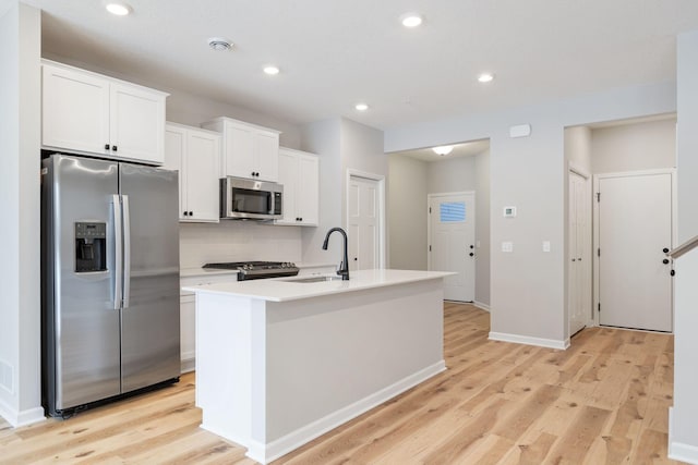 23225 Creekview Ct, Rogers, MN 55374 - kitchen with stainless steel appliances, a sink, light wood-style floors, an island with sink, and recessed lighting