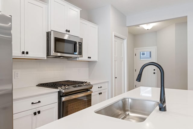 23225 Creekview Ct, Rogers, MN 55374 - kitchen with stainless steel appliances, a sink, decorative backsplash, white cabinetry, and light countertops