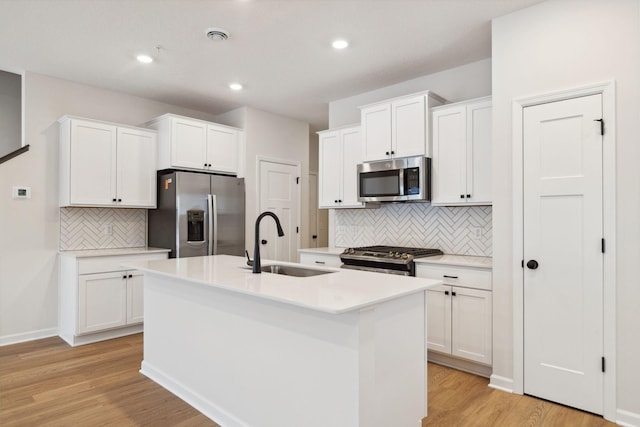 23229 Creekview Ct, Rogers, MN 55374 - kitchen with appliances with stainless steel finishes, a sink, backsplash, an island with sink, and light wood finished floors