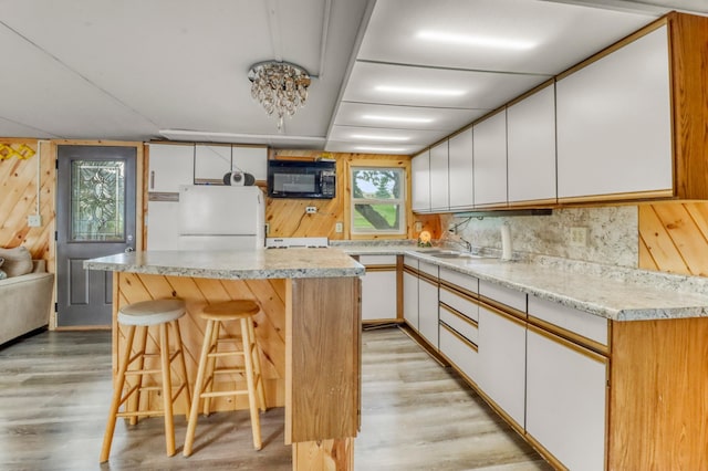 24505 Twilight Ln, Lida Twp, MN 56572 - kitchen featuring freestanding refrigerator, black microwave, light wood-style flooring, white cabinetry, and light countertops