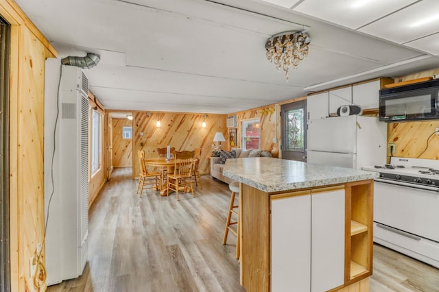 24505 Twilight Ln, Lida Twp, MN 56572 - kitchen featuring white appliances, light wood-type flooring, a heating unit, wooden walls, and a center island