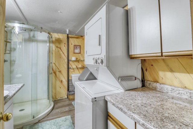 24505 Twilight Ln, Lida Twp, MN 56572 - washroom with stacked washer / drying machine, light wood-type flooring, and wood walls