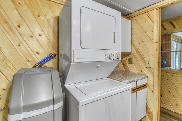 24505 Twilight Ln, Lida Twp, MN 56572 - laundry room with stacked washing machine and dryer, wood walls, cabinet space, and wood finished floors