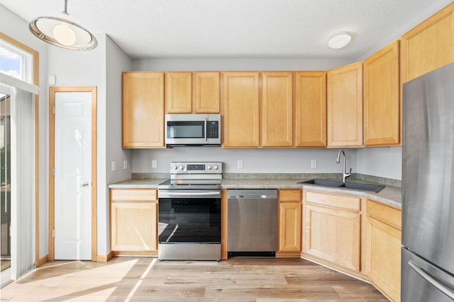 4107 Regent Ave N, Robbinsdale, MN 55422 - kitchen with stainless steel appliances, light brown cabinets, a sink, light wood finished floors, and light countertops
