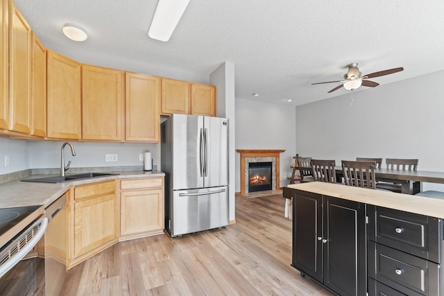 4107 Regent Ave N, Robbinsdale, MN 55422 - kitchen with stainless steel appliances, light brown cabinetry, light countertops, light wood-style flooring, and a ceiling fan