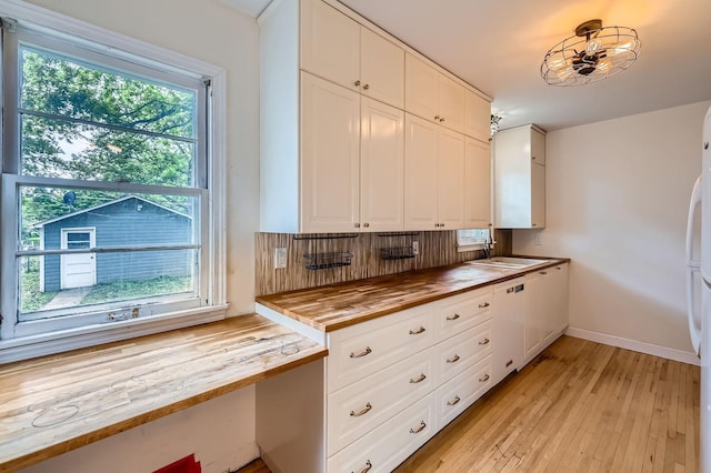 583 Cromwell Ave, Saint Paul, MN 55104 - kitchen featuring butcher block countertops, white appliances, white cabinets, light wood finished floors, and a sink