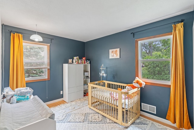 9301 Northwood Pkwy, New Hope, MN 55427 - bedroom featuring multiple windows, wood finished floors, and a nursery area