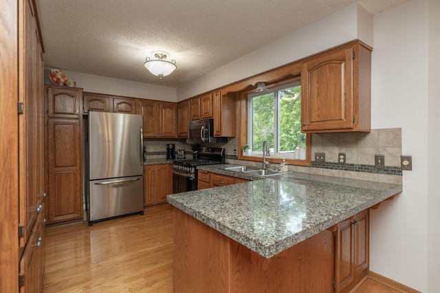 8821 Jonquil Ln N, Maple Grove, MN 55369 - kitchen with appliances with stainless steel finishes, a sink, a peninsula, light wood finished floors, and brown cabinets