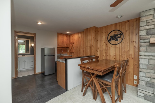 8821 Jonquil Ln N, Maple Grove, MN 55369 - dining room with wood walls, ceiling fan, dark tile patterned floors, and bar area