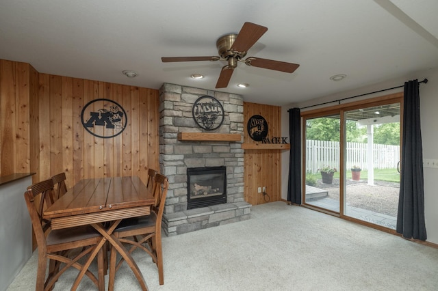 8821 Jonquil Ln N, Maple Grove, MN 55369 - carpeted dining space featuring ceiling fan, wood walls, and a stone fireplace
