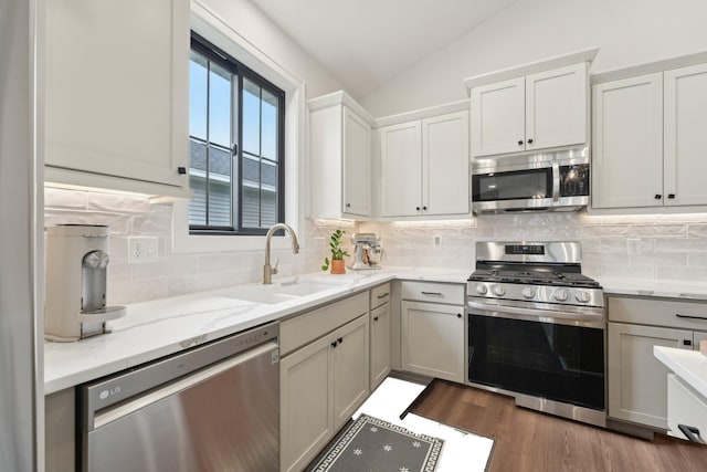 25822 Emerson Ct, Wyoming, MN 55092 - kitchen featuring appliances with stainless steel finishes, a sink, vaulted ceiling, backsplash, and light stone countertops
